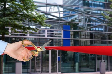 Image of Man cutting red ribbon at opening ceremony of hotel, closeup