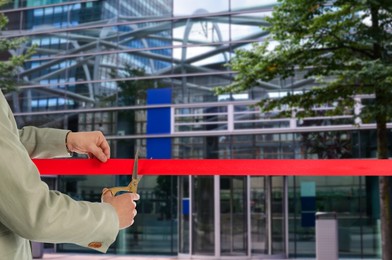 Image of Man cutting red ribbon at opening ceremony of hotel, closeup
