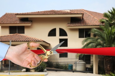 Image of Man cutting red ribbon at opening ceremony of housing estate, closeup