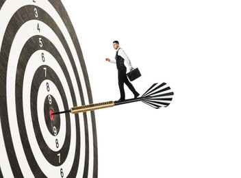 Image of Goal achievement, business success and targeting. Businessman walking on dart sticking in center of dartboard against white background