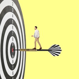 Image of Targeting, goal achievement. Art collage with businessman walking on dart sticking in center of dartboard against yellow background