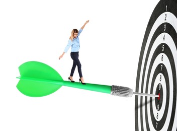 Image of Concepts of targeting, decision and goal achievement. Businesswoman walking on dart sticking in center of dartboard against white background