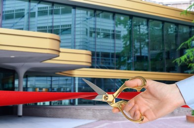 Image of Man cutting red ribbon at opening ceremony of hotel, closeup