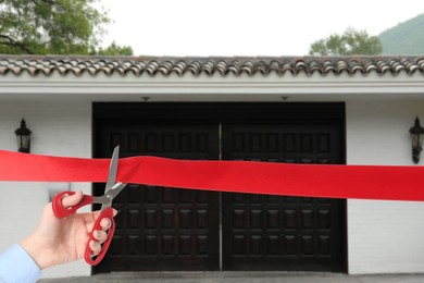 Image of Man cutting red ribbon at opening ceremony of house, closeup