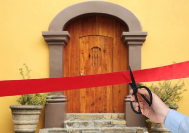 Image of Man cutting red ribbon at opening ceremony of house, closeup