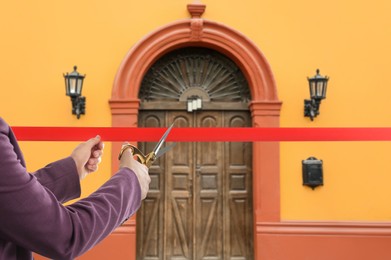 Image of Woman cutting red ribbon at opening ceremony of house, closeup