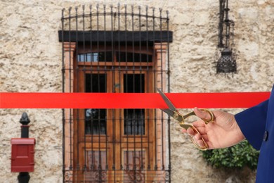 Image of Man cutting red ribbon at opening ceremony of house, closeup