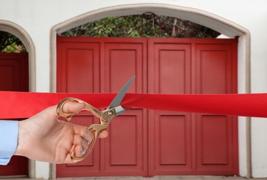 Image of Man cutting red ribbon at opening ceremony of house, closeup