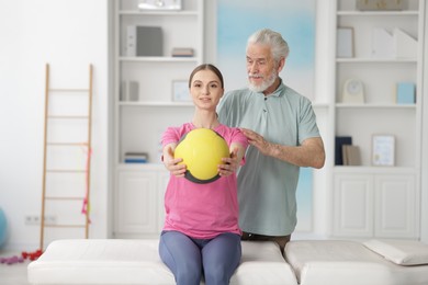 Photo of Doctor and patient exercising with medicine ball in clinic