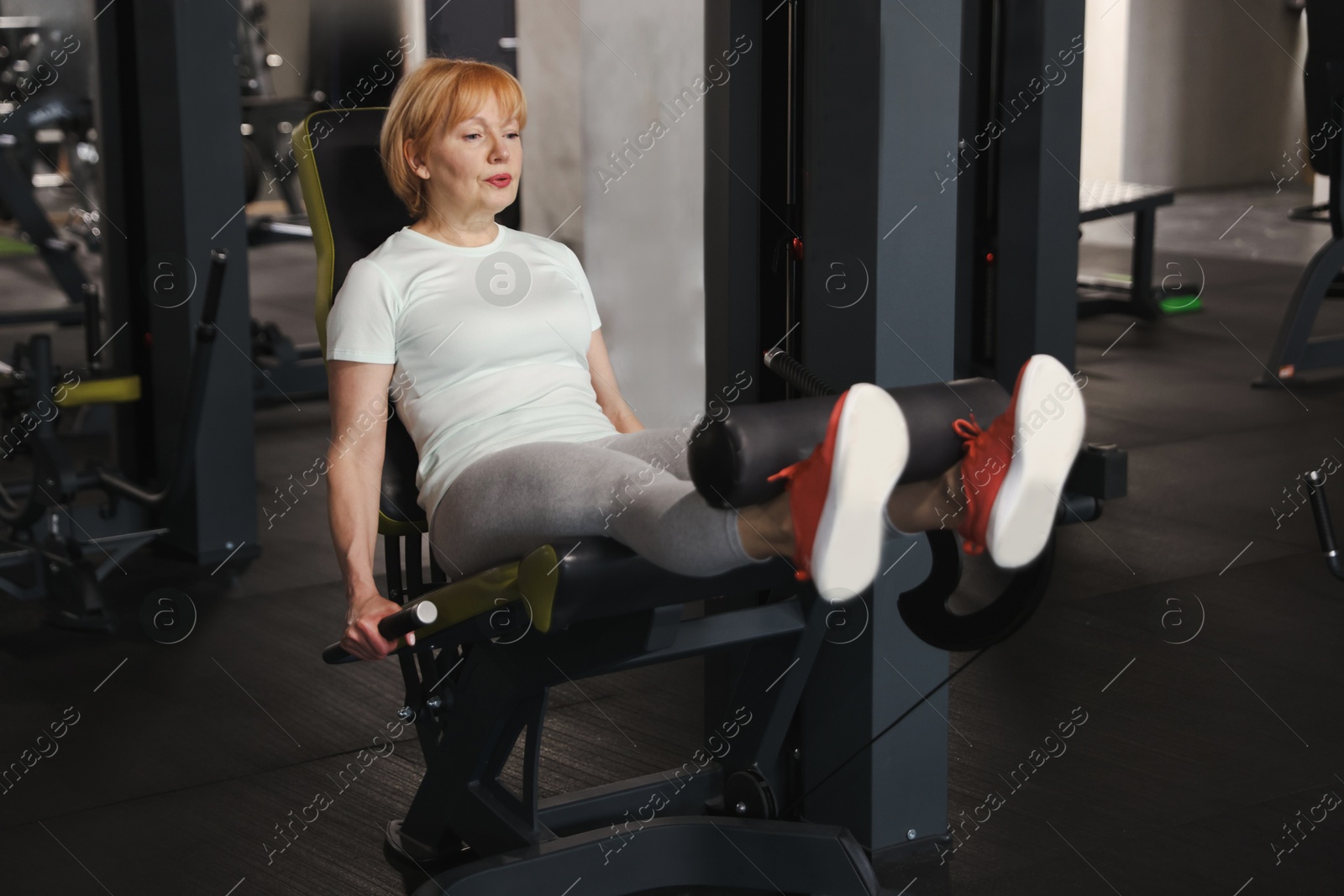 Senior woman training on leg extension machine in gym Photo of Senior woman training on leg extension machine in gym