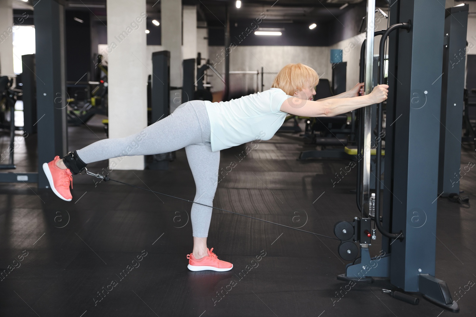 Senior woman training on cable machine in gym Photo of Senior woman training on cable machine in gym