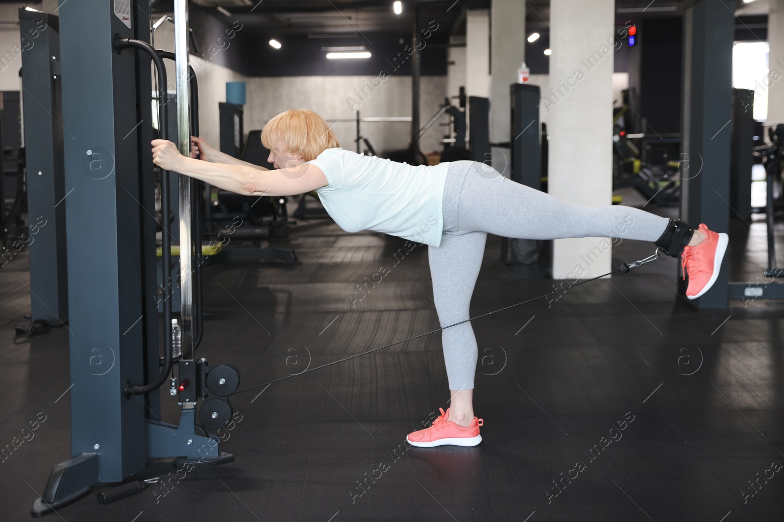 Senior woman training on cable machine in gym Photo of Senior woman training on cable machine in gym