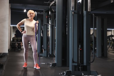 Photo of Senior woman exercising with fitness elastic band in gym