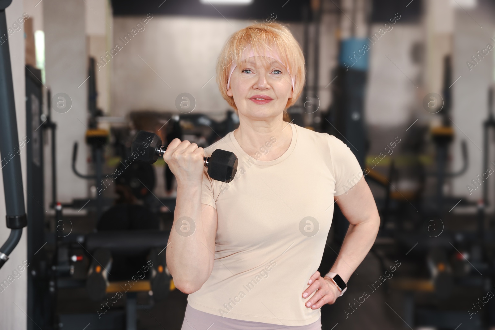 Senior woman training with dumbbell in gym Photo of Senior woman training with dumbbell in gym