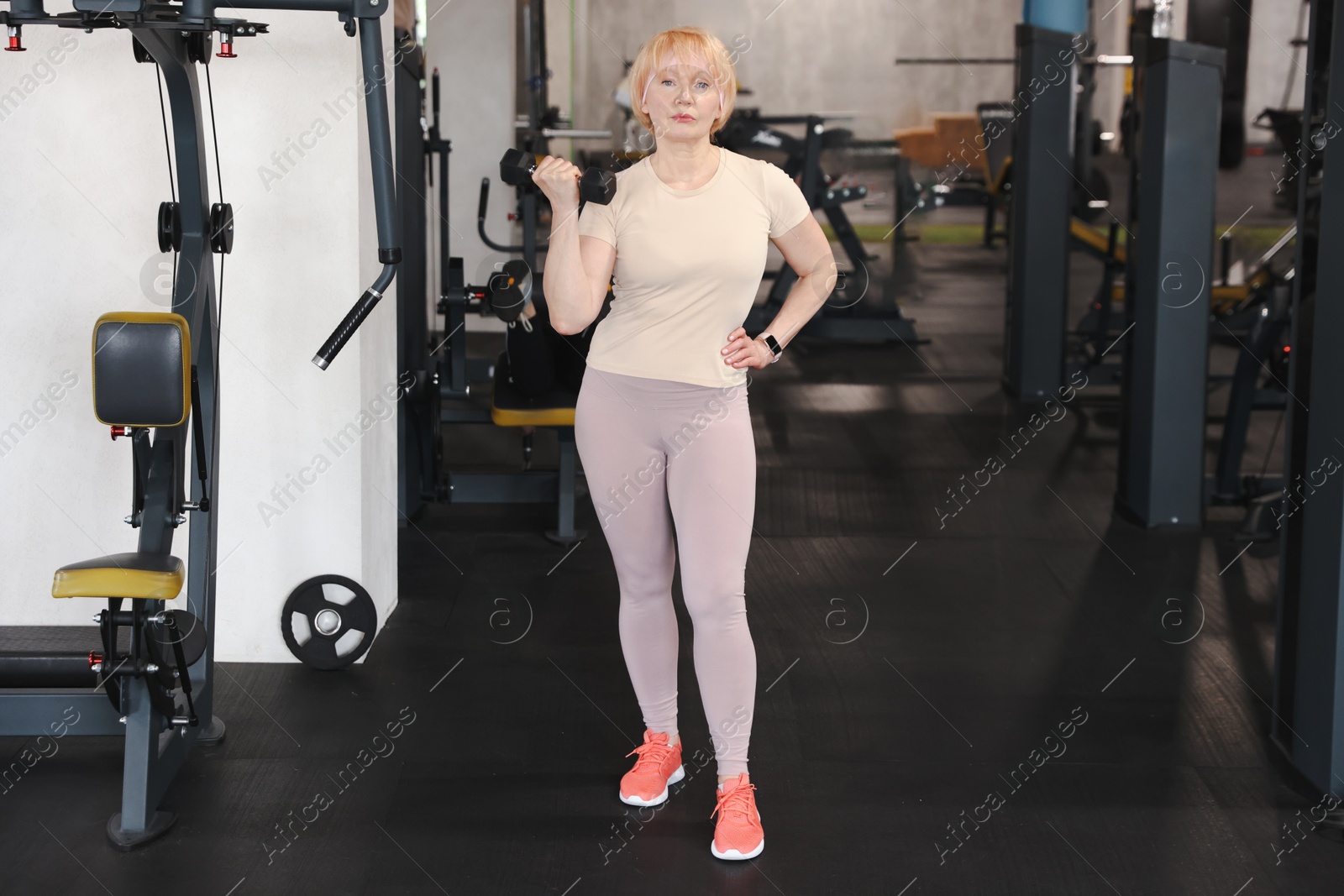 Senior woman training with dumbbell in gym Photo of Senior woman training with dumbbell in gym