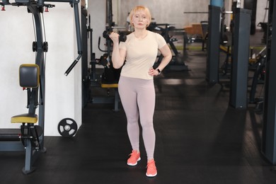 Photo of Senior woman training with dumbbell in gym