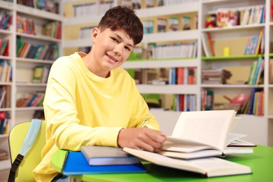 Photo of Student with books studying at table in library