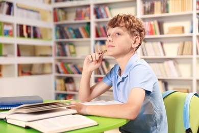 Photo of Student with books studying at table in library. Space for text