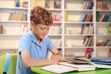 Photo of Student with books studying at table in library. Space for text