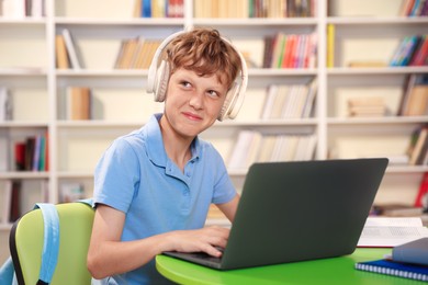 Photo of Student with laptop studying at table in library