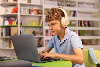 Photo of Student with laptop studying at table in library