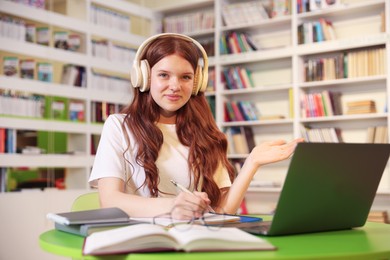 Photo of Student with laptop studying at table in library