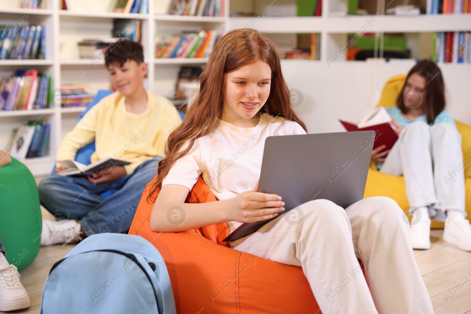 Student with laptop studying on bean bag in library Photo of Student with laptop studying on bean bag in library