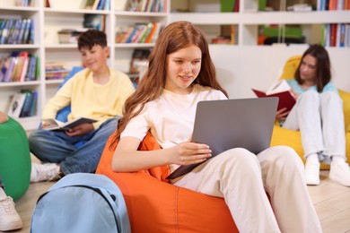 Photo of Student with laptop studying on bean bag in library