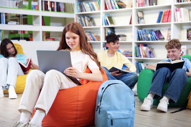 Photo of Student with laptop studying on bean bag in library