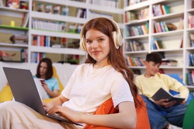 Photo of Student with laptop studying on bean bag in library
