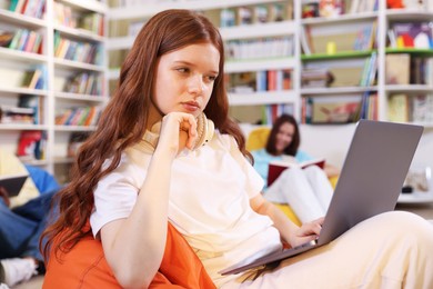 Photo of Student with laptop studying on bean bag in library