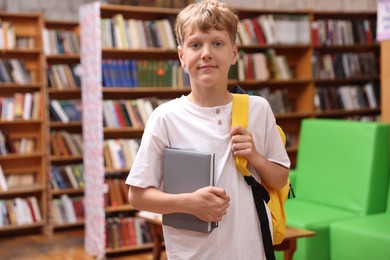 Photo of Student with book and backpack in library