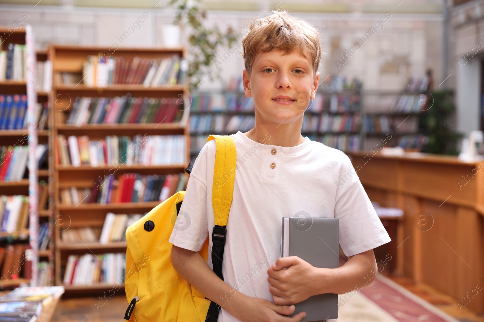 Student with book and backpack in library Photo of Student with book and backpack in library