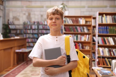 Photo of Student with book and backpack in library