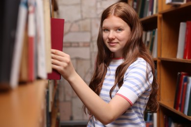 Photo of Student taking book out of shelf in library