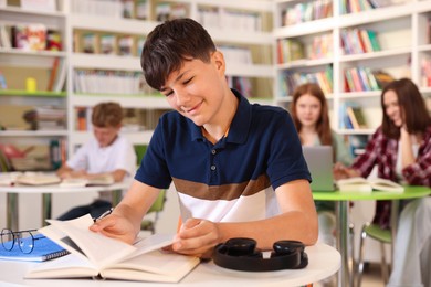 Photo of Student with books studying at table in library