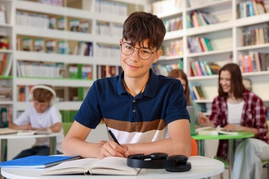 Photo of Student with books studying at table in library
