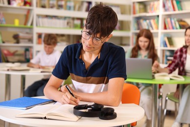 Photo of Student with books studying at table in library