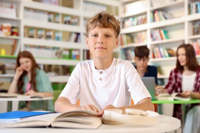 Photo of Student with books studying at table in library