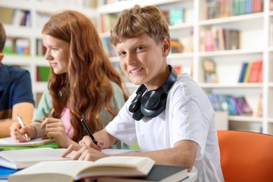 Photo of Students with books studying together at table in library