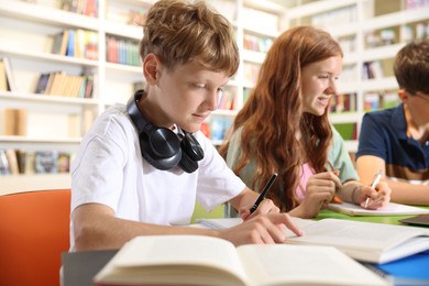 Photo of Students with books studying together at table in library