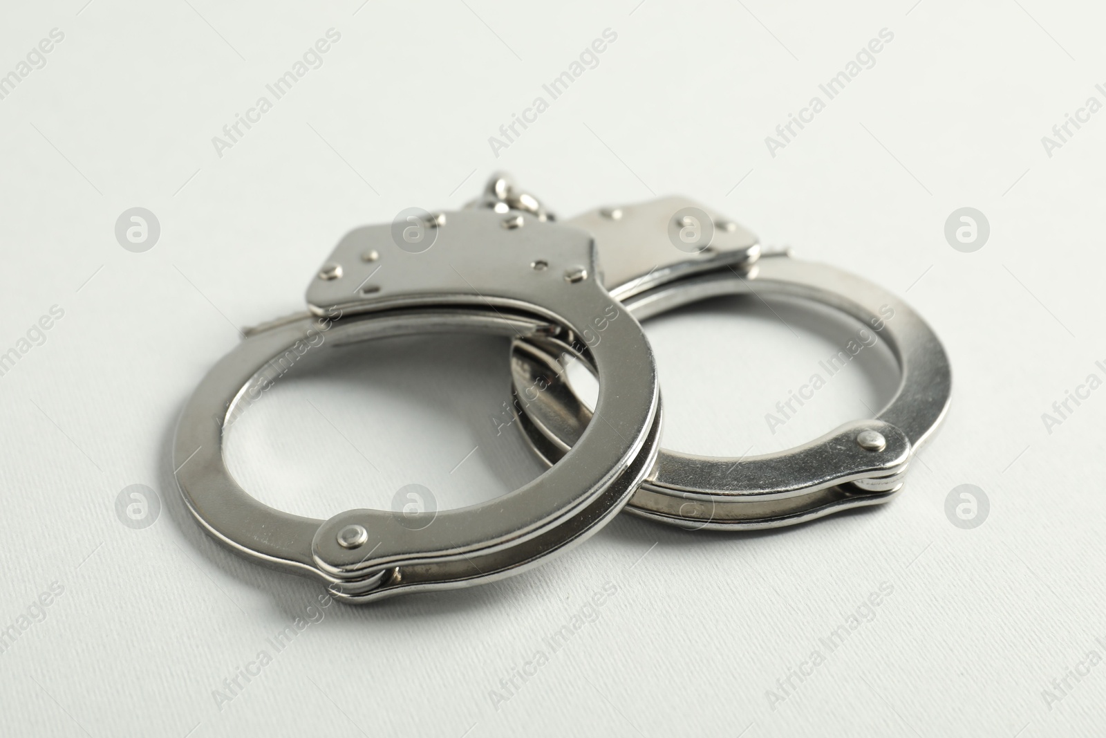 Handcuffs on white background, closeup. Police equipment Photo of Handcuffs on white background, closeup. Police equipment