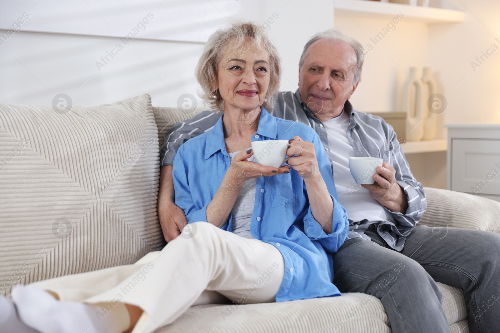 Lovely senior couple enjoying hot drinks on sofa at home Photo of Lovely senior couple enjoying hot drinks on sofa at home