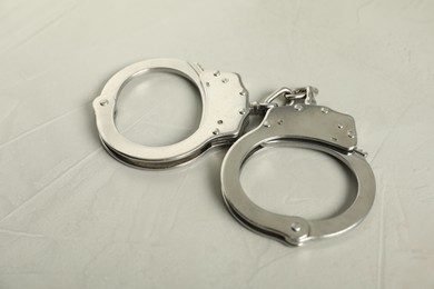 Photo of Handcuffs on light grey table, closeup. Police equipment