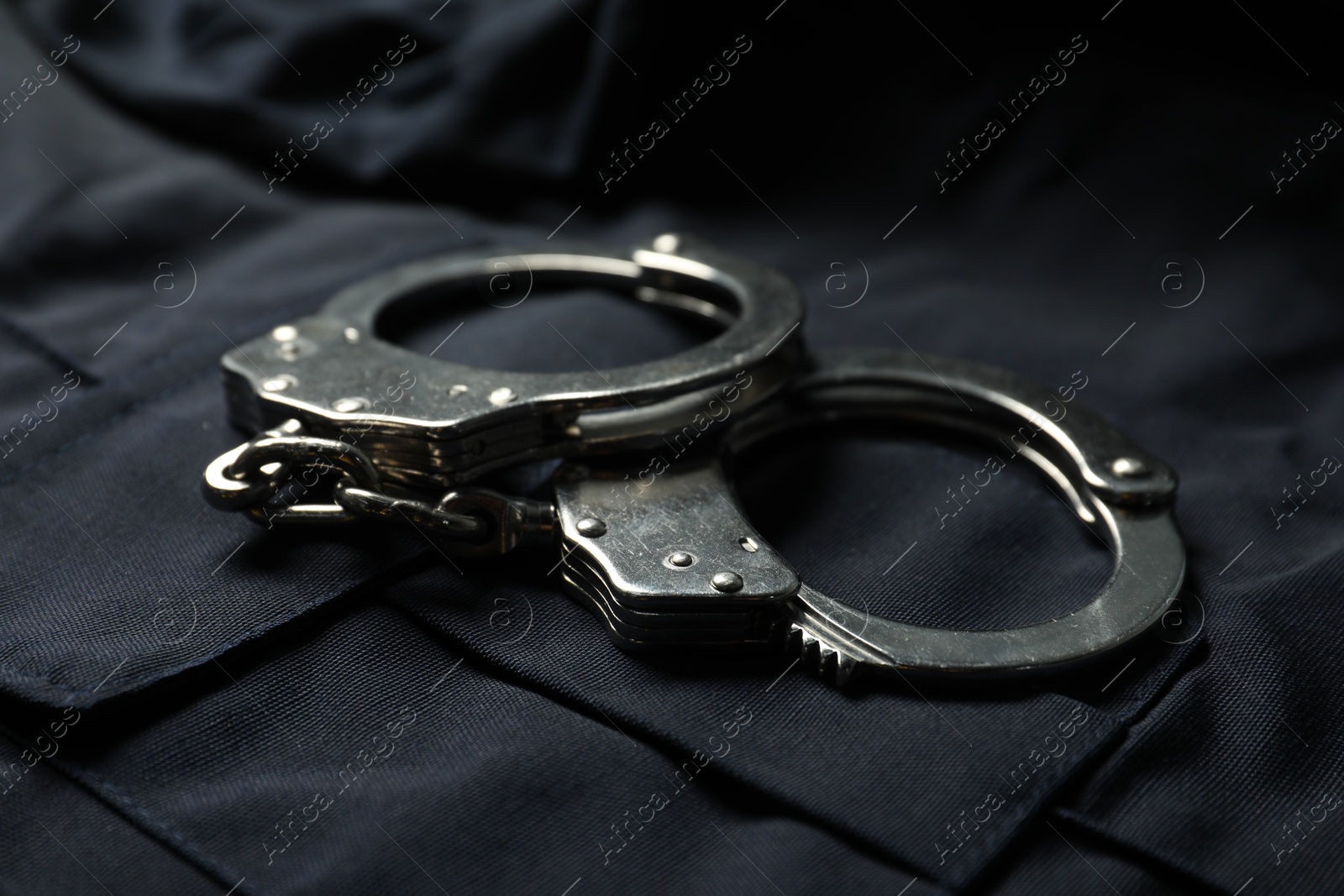 Handcuffs on dark blue police uniform, closeup Photo of Handcuffs on dark blue police uniform, closeup
