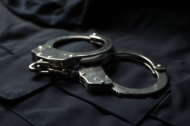 Photo of Handcuffs on dark blue police uniform, closeup
