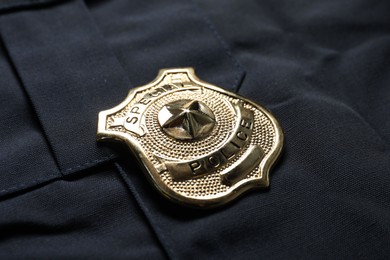 Photo of Police badge on dark blue uniform, closeup