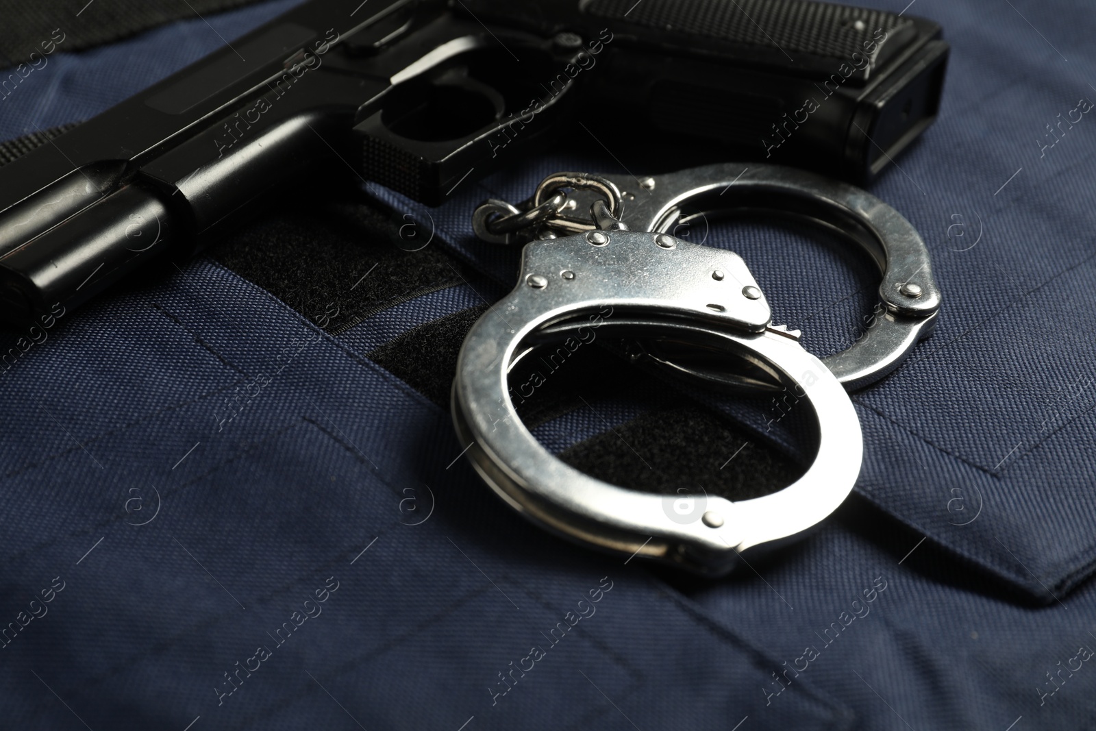 Handcuffs and gun on bulletproof vest, closeup. Police equipment Photo of Handcuffs and gun on bulletproof vest, closeup. Police equipment
