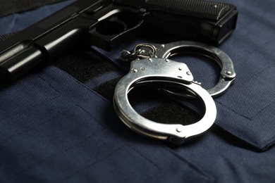 Photo of Handcuffs and gun on bulletproof vest, closeup. Police equipment