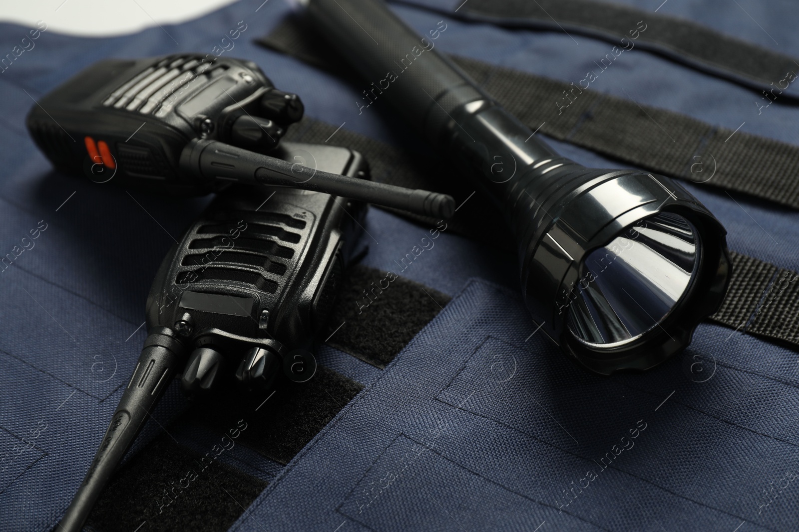 Flashlight and walkie talkies on bulletproof vest, closeup. Police equipment Photo of Flashlight and walkie talkies on bulletproof vest, closeup. Police equipment